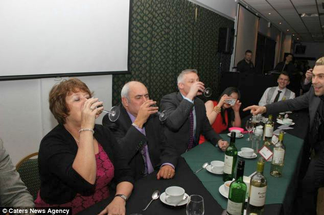 Three senior members of staff engaging in a drinking game in front of an audience